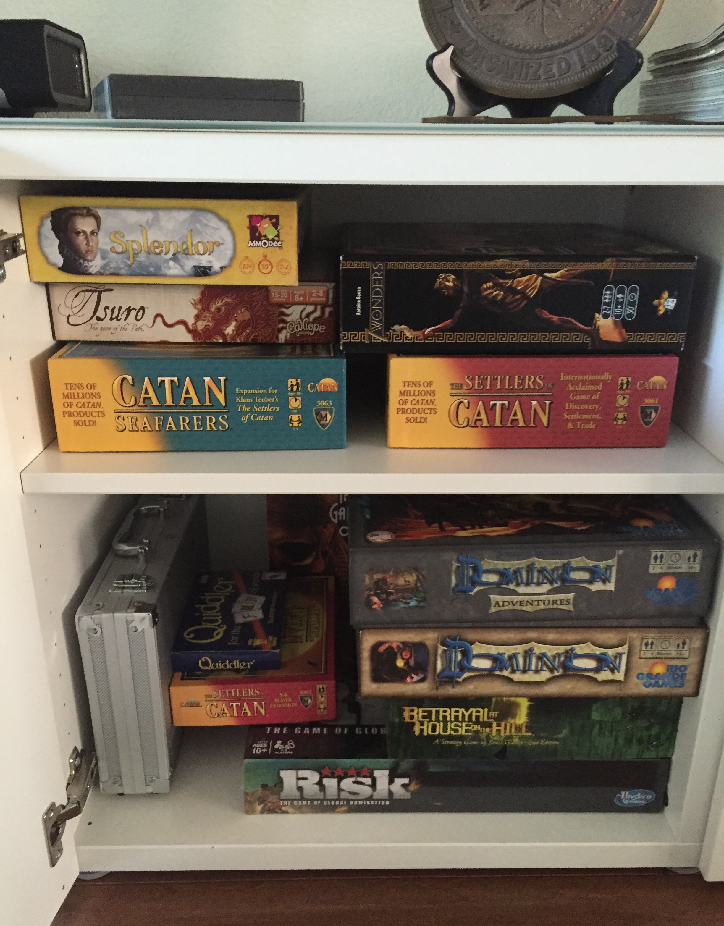 Game cabinet filled with games including Settlers of Catan for game night