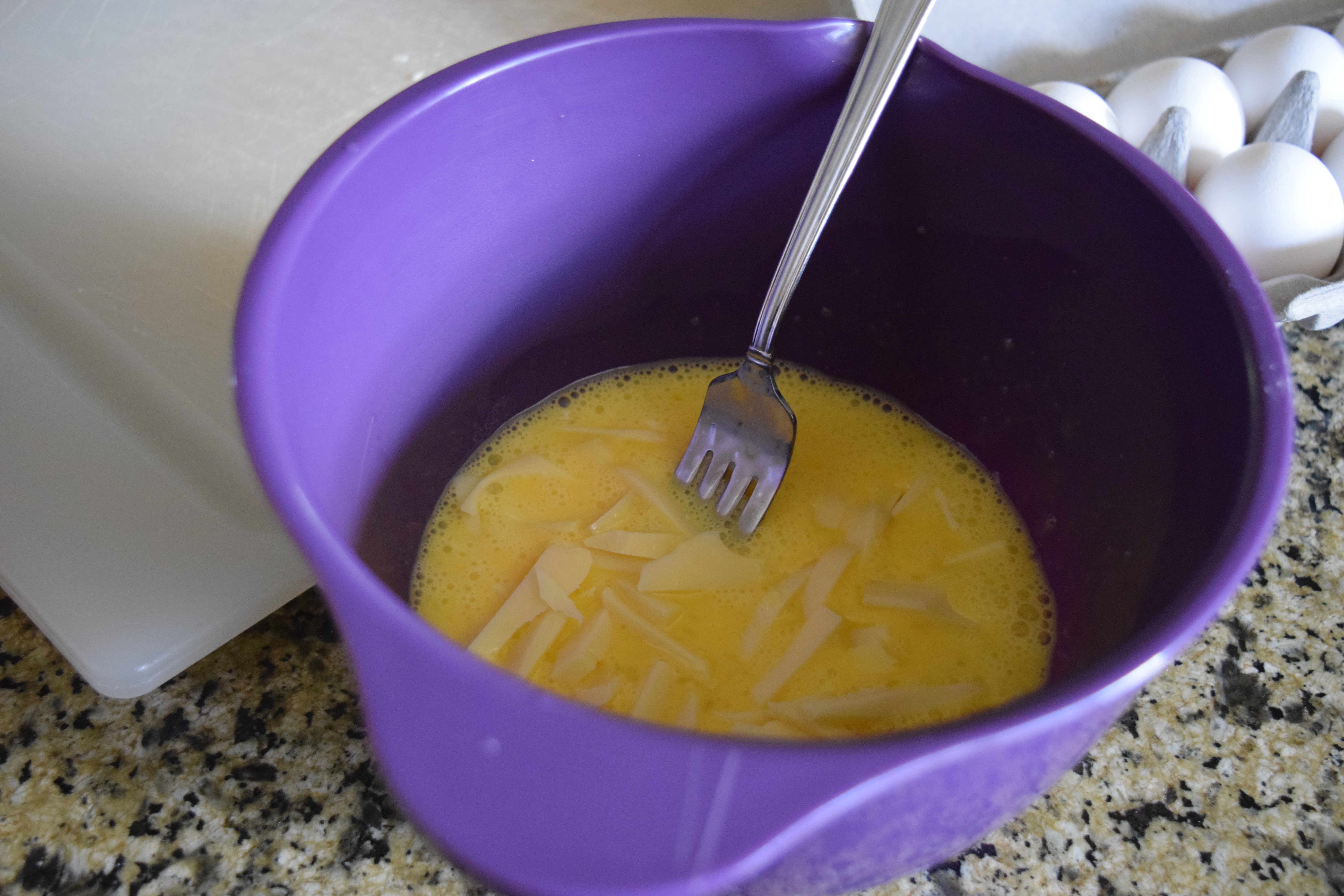 Eggs beaten in mixing bowl with cheese
