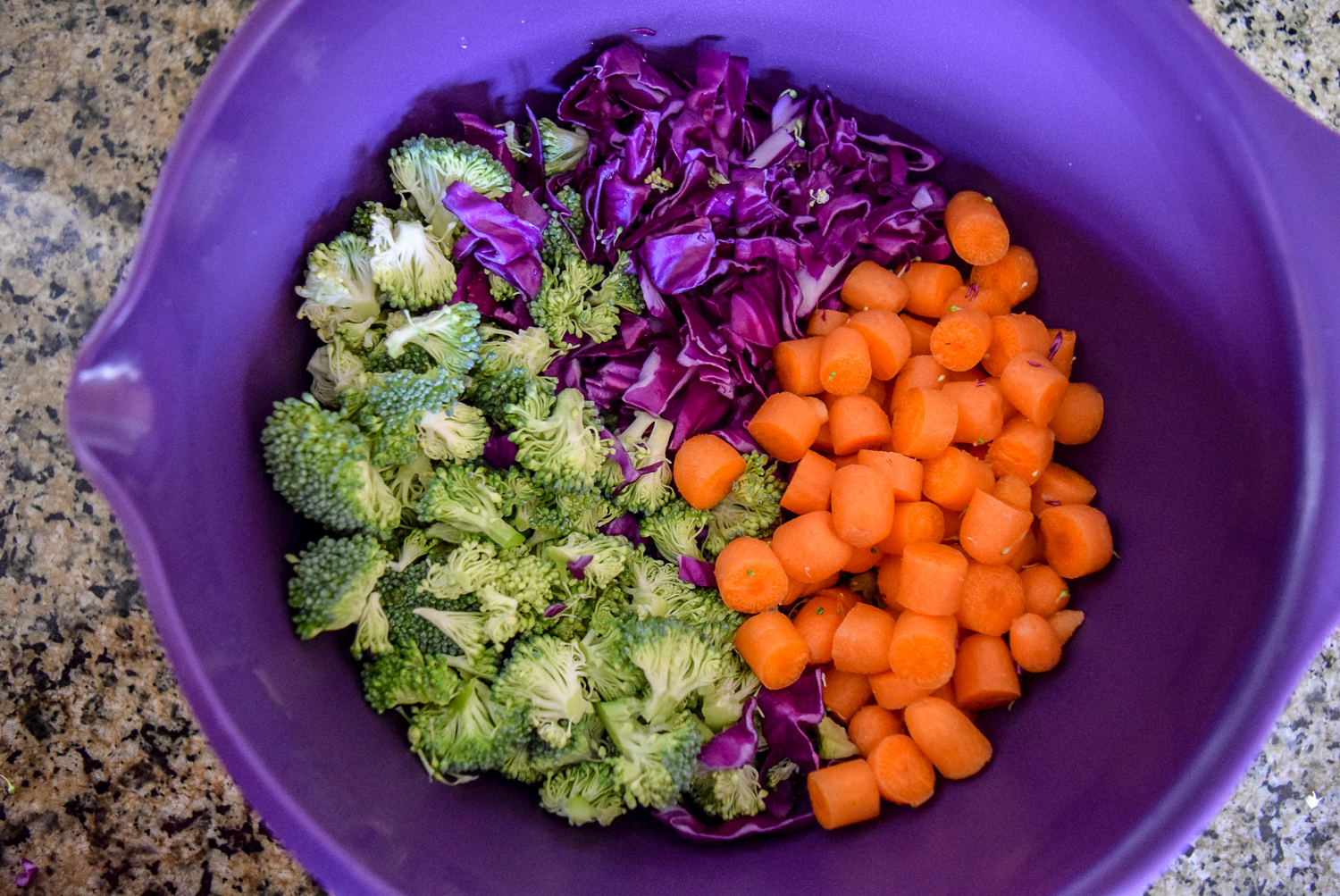 Chopped red cabbage, broccoli, and carrots in mixing bowl before mixing into Sunshine Spicy Mustard Tahini Cruciferous Slaw