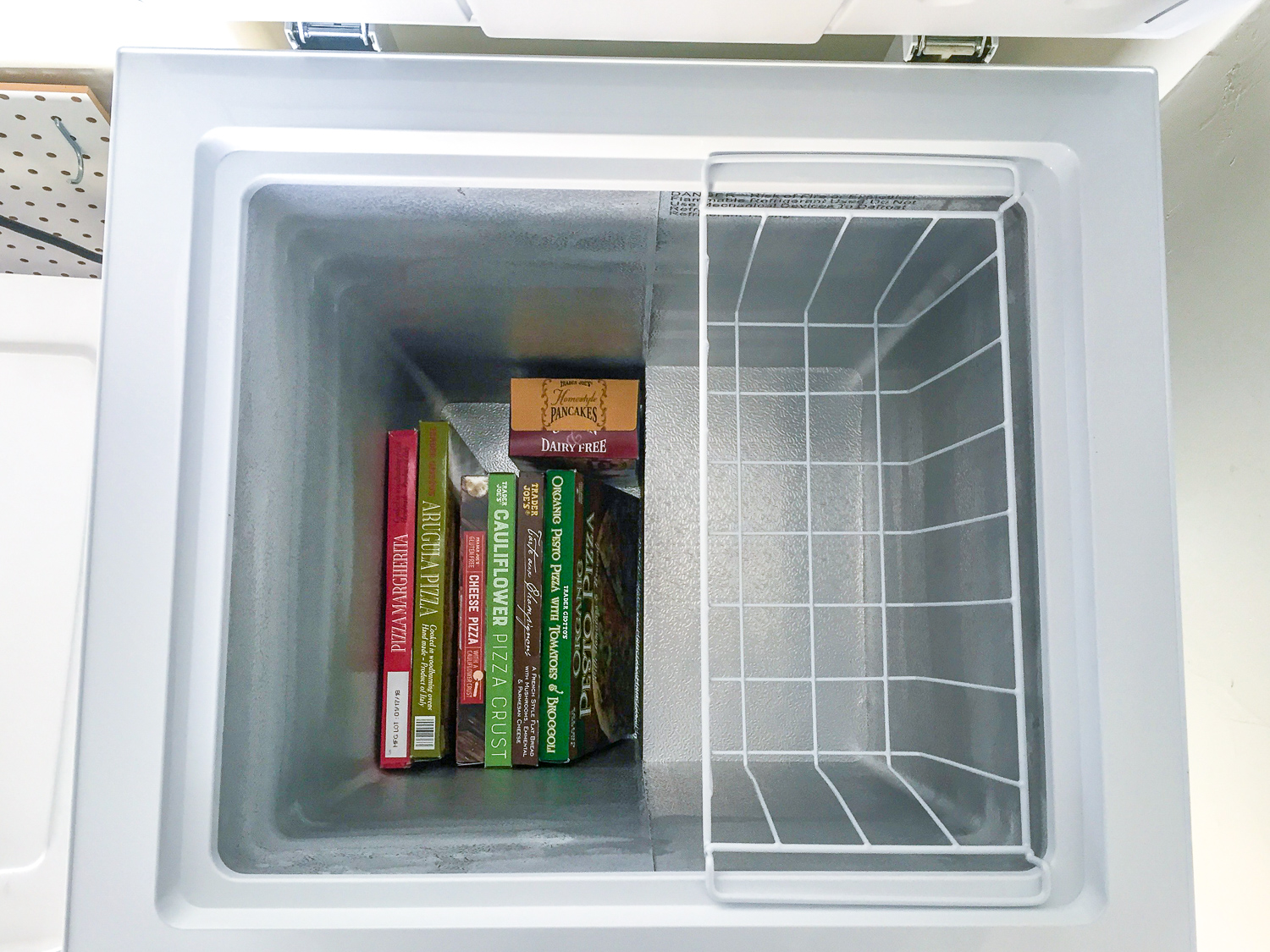 Top view of open inside of Insignia 3.5 Cu. Ft. Chest Freezer filled with Trader Joe's frozen pizzas