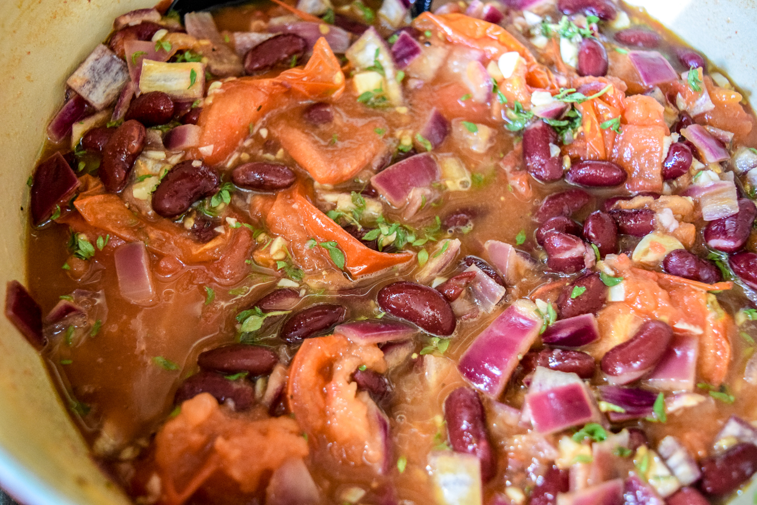 Roasted tomatoes, red onions, garlic, and kidney beans before simmering in oven with thyme herb for Egg-White Chili Shakshuka