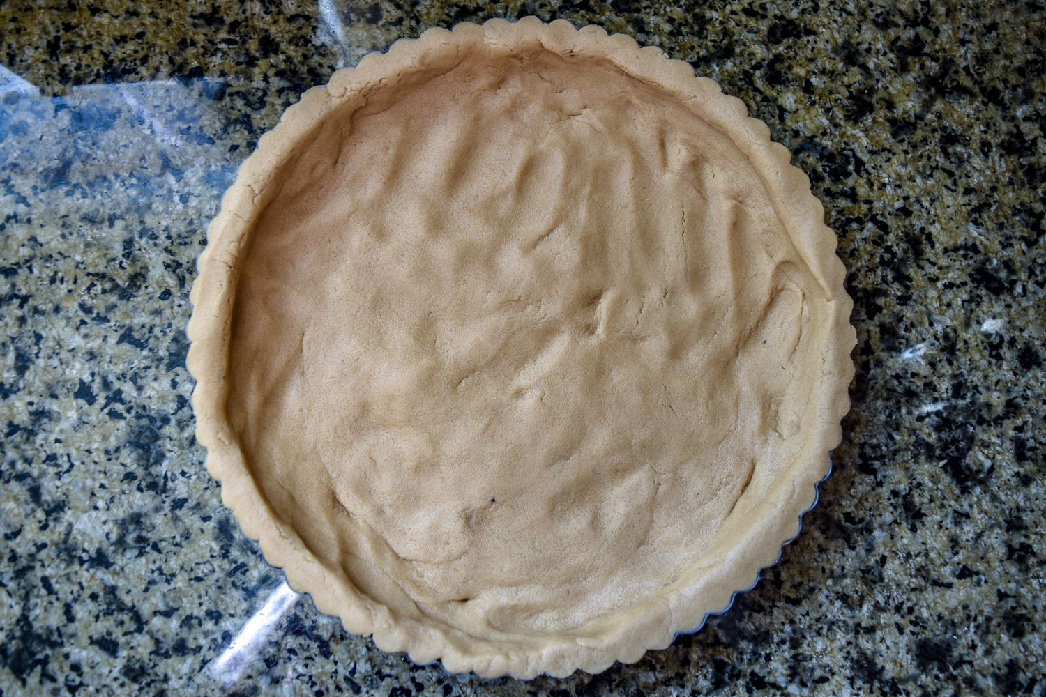 Shortbread dough pressed into tart pan from top