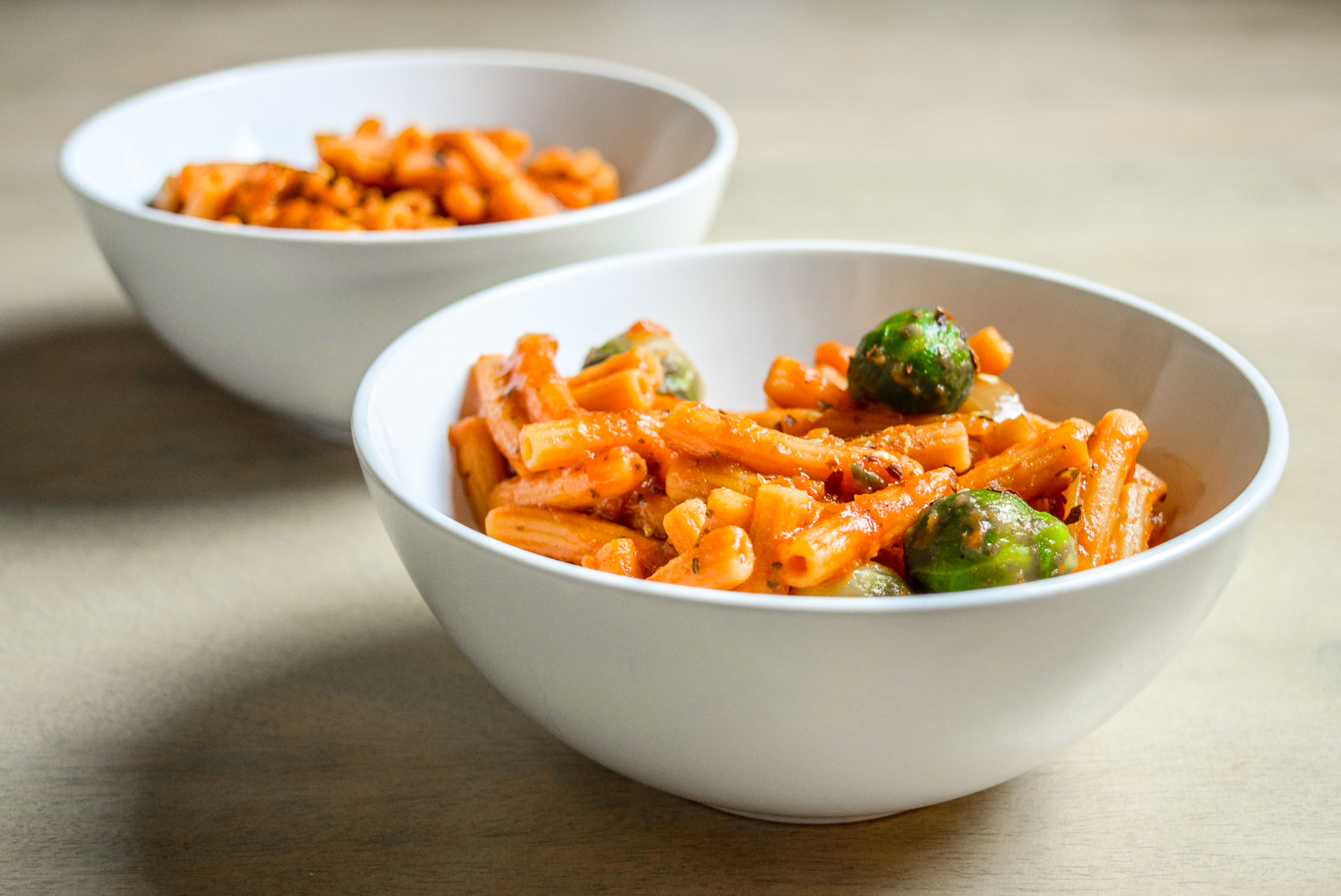 Finished Protein-Packed Red Lentil Pasta with Marinara, Brussel Sprouts, and Caramelized Onions in two bowls