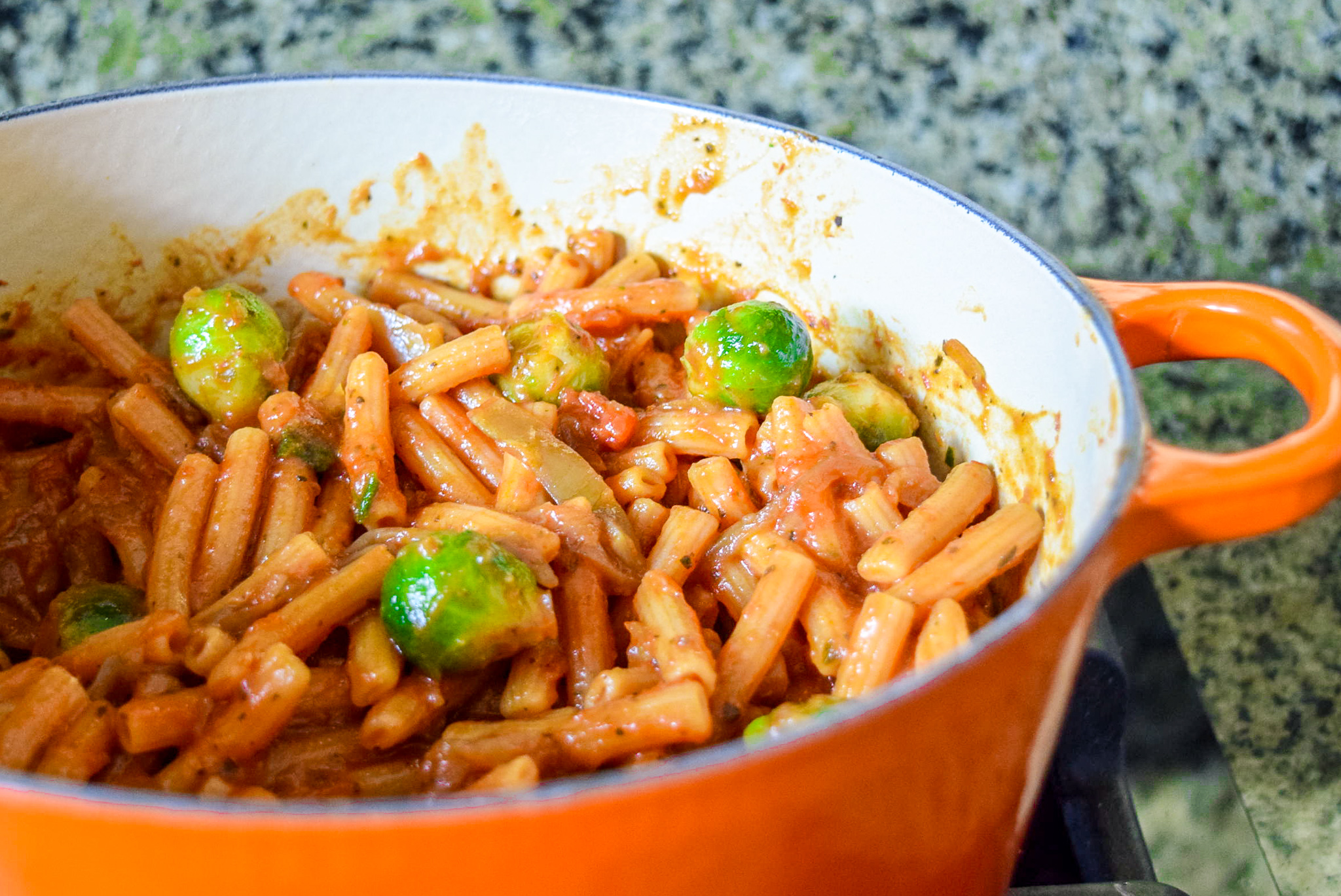 Trader Giotto’s Organic Red Lentil Sedanini Pasta in Flame Le Creuset Dutch Oven tossed with marinara sauce, brussel sprouts, and caramelized onions