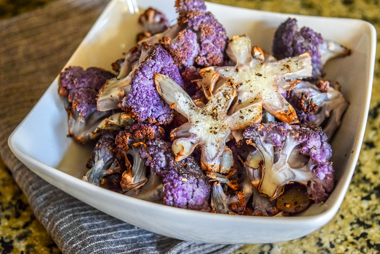 Finished roasted purple cauliflower florets garnished with stem pieces