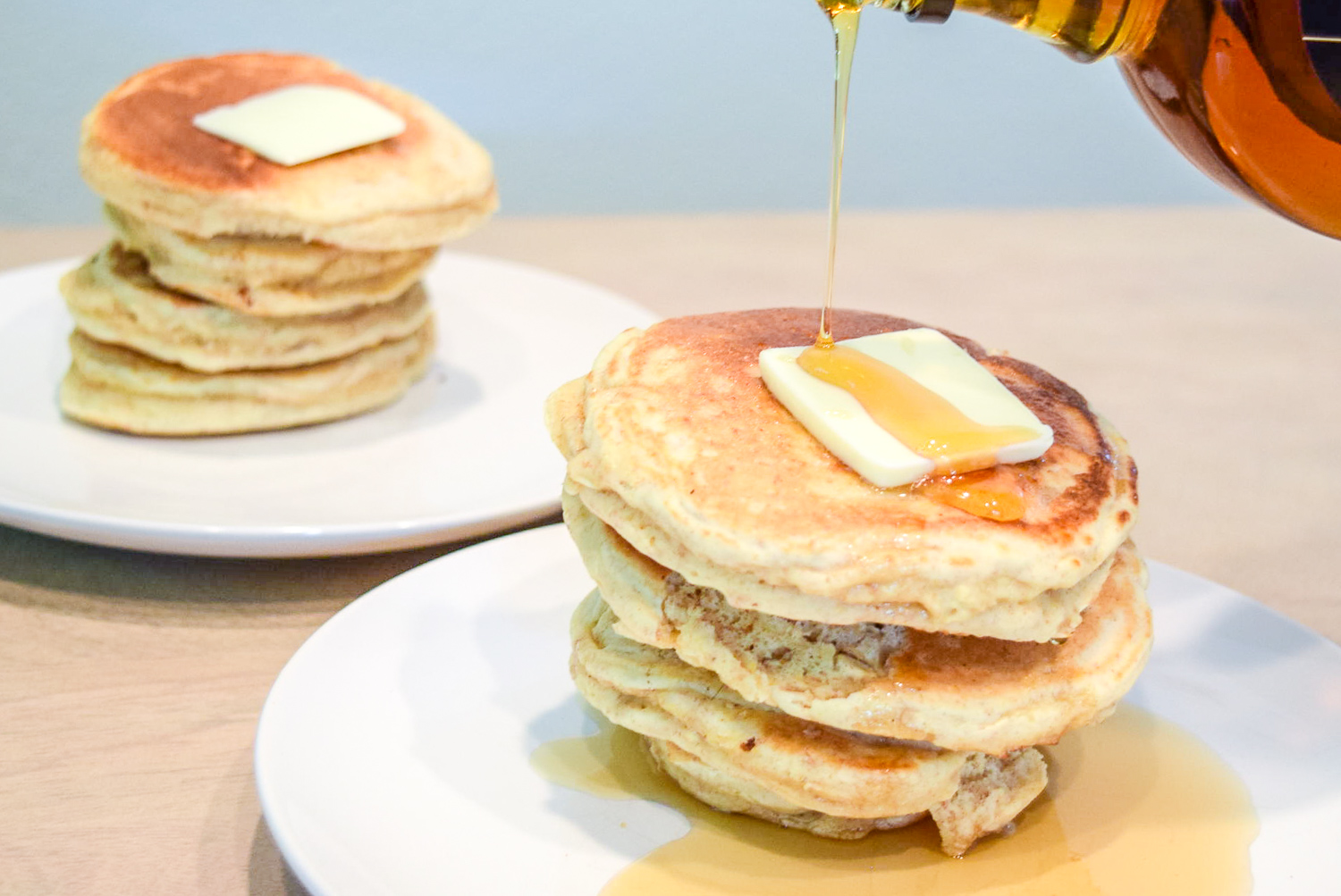 Pouring maple syrup onto Trader Joe's Multigrain Pancake Mix stack with butter