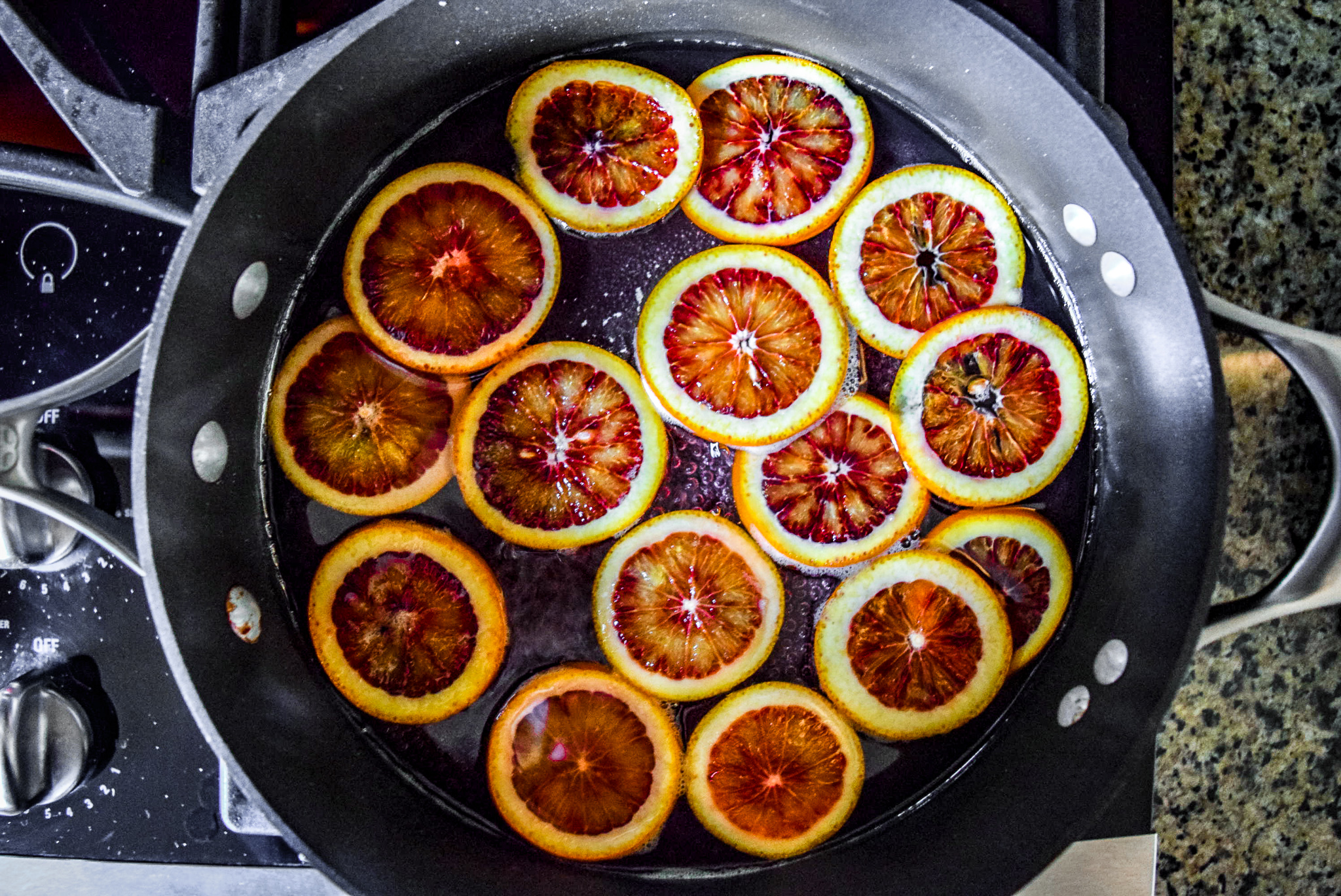Blood orange slices in sugar water for candying from top