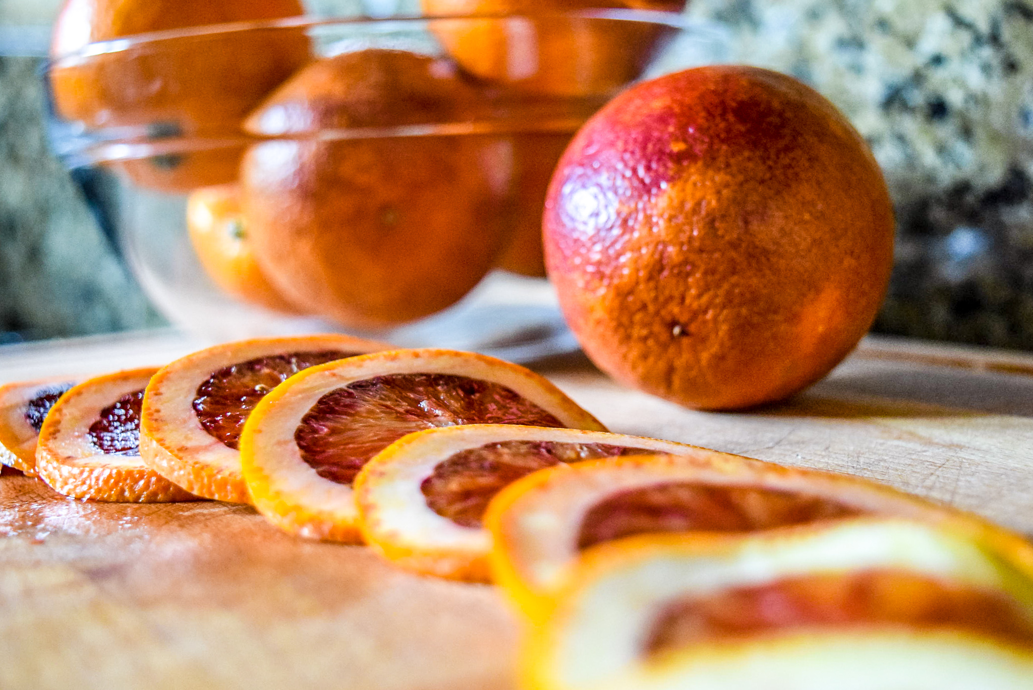 Sliced blood orange rounds in preparation for candying from front up close