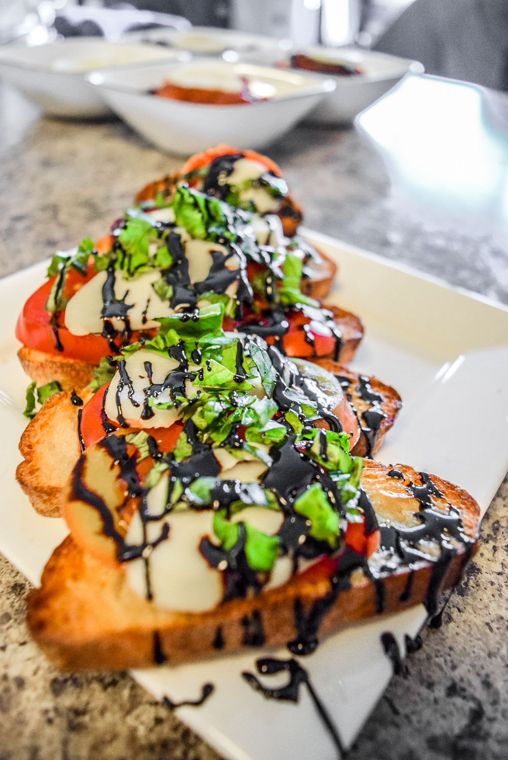 Finished caprese bruschetta with heirloom tomato, fresh basil, homemade mozzerella, and balsamic reduction from angle