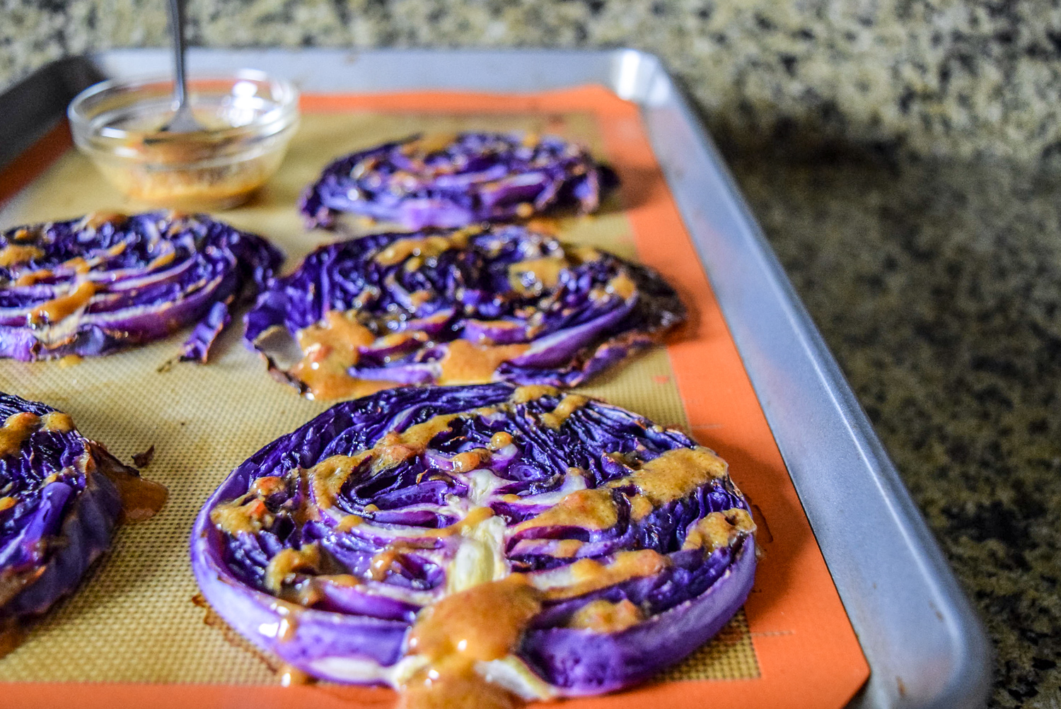 One pan meal of roasted red cabbage steaks drizzled with chili miso sauce from side