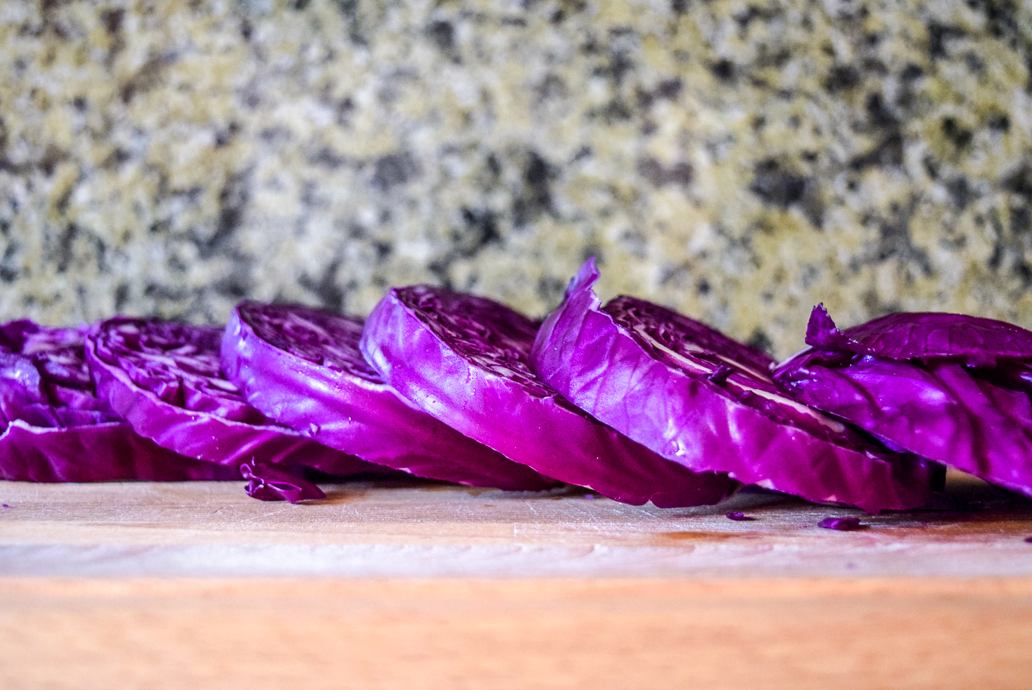 Sliced red cabbage steaks on wooden cuttingboard from side